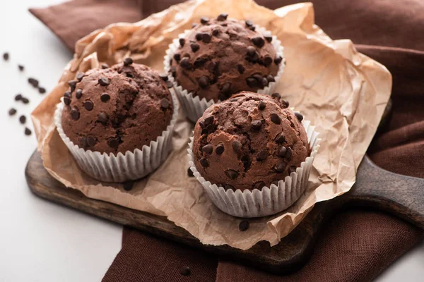 Frische Schokoladenmuffins auf Holzschneidebrett auf brauner Serviette — Stockfoto