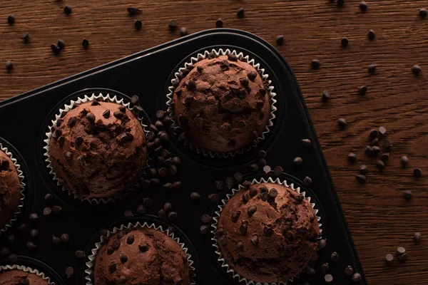 Vue du dessus des muffins au chocolat frais dans une boîte à muffins sur une surface en bois — Photo de stock