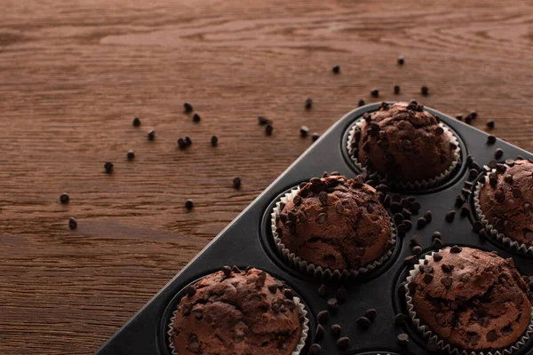 Close up view of fresh chocolate muffins in muffin tin on wooden surface — Stock Photo
