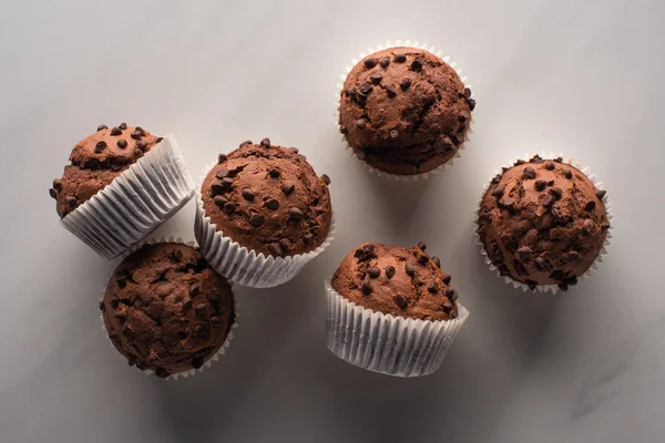 Вид сверху на свежие шоколадные кексы на мраморной поверхности — стоковое фото