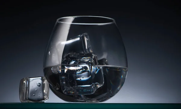 Transparentes Glas mit Eiswürfeln und Wodka im Dunkeln mit Gegenlicht — Stockfoto