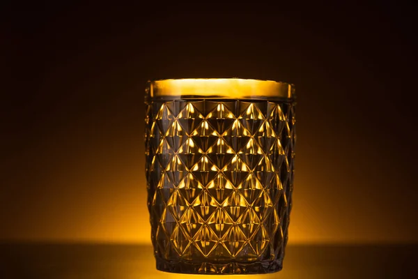 Facettiertes Glas im Dunkeln mit warmem Gegenlicht — Stockfoto