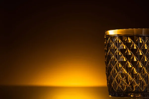 Facettiertes Glas im Dunkeln mit warmem Gegenlicht — Stockfoto