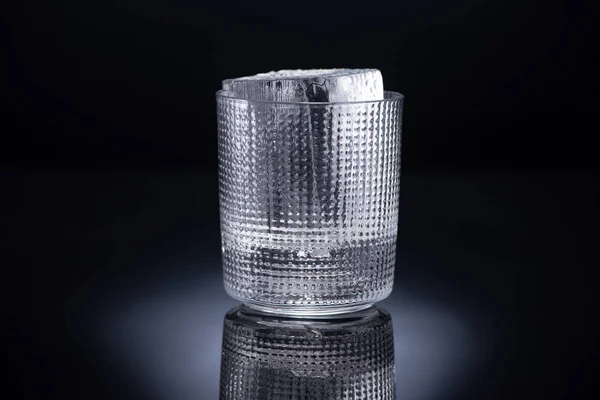 Фацетне скло з кубиком льоду на чорному фоні — стокове фото