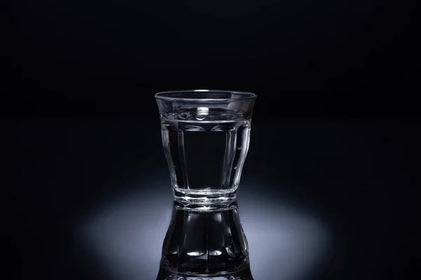 Vidro transparente com líquido sobre fundo preto — Fotografia de Stock