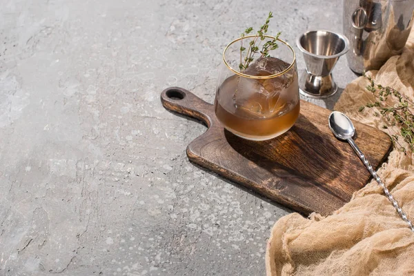 Vetro trasparente con erbe, cubetti di ghiaccio e whisky su superficie in calcestruzzo con attrezzature bar — Foto stock