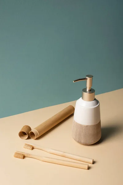 Cepillos de dientes, estuche de cepillo de dientes, dispensador de jabón líquido en beige y gris, concepto de cero residuos - foto de stock