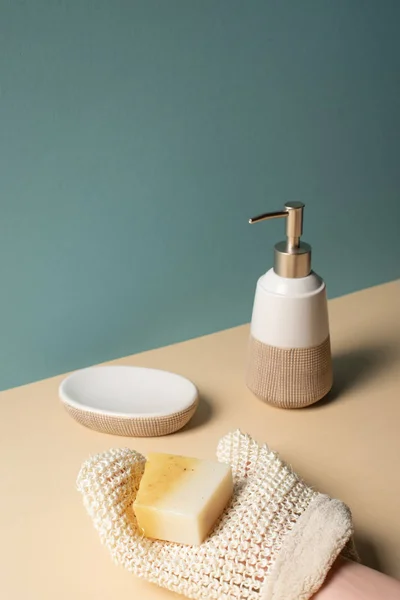 Cropped view of woman holding soap above surface near dispenser, soap dish on beige and grey, zero waste concept — Stock Photo