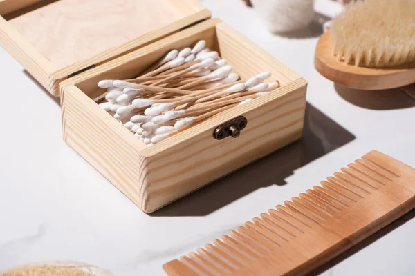 Вибірковий фокус коробки вушних паличок, гребінця та щітки для волосся на білому тлі, концепція нульових відходів — стокове фото