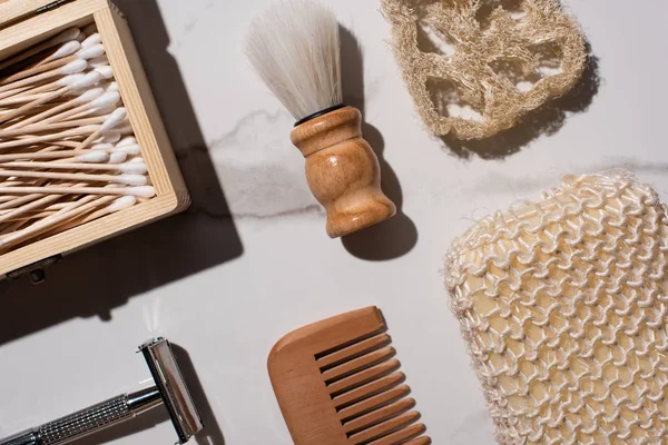 Top view of comb, razor, sponges, box of ear sticks and shaving brush on white background, zero waste concept — Stock Photo