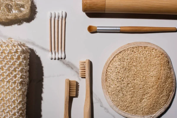 Vista dall'alto di spugne, auricolari, spazzolini da denti, spazzolino cosmetico su sfondo bianco, concetto di zero rifiuti — Foto stock