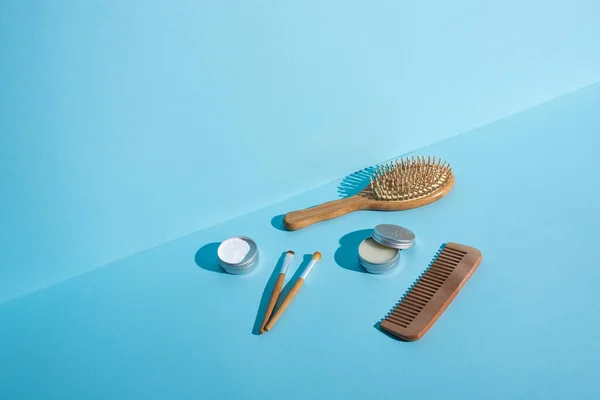 Brosse à cheveux, peigne, bocaux de cire et de poudre à dents, brosses cosmétiques sur fond bleu, concept zéro déchet — Photo de stock