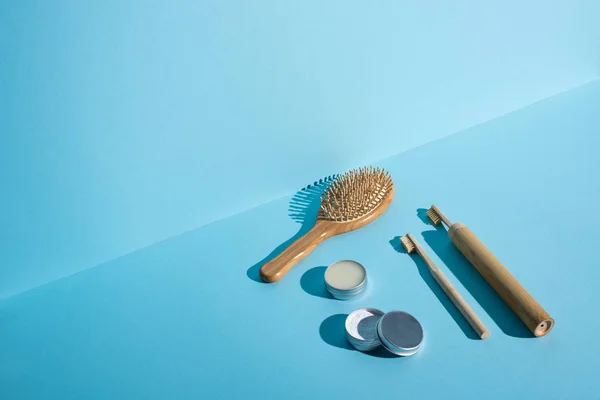Escova de cabelo, frascos de cera e pó de dente, escovas de dentes em fundo azul, conceito de desperdício zero — Fotografia de Stock