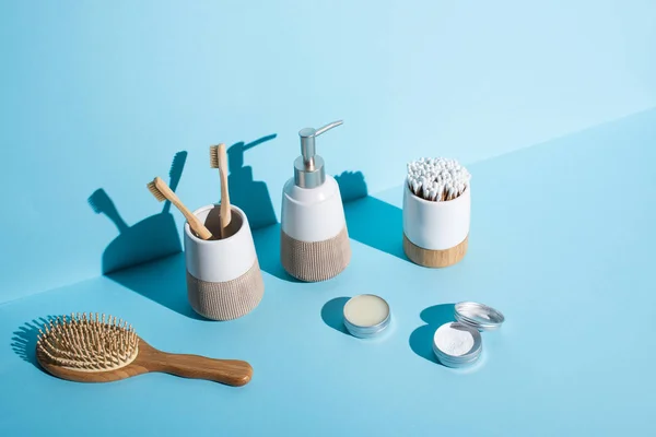Gläser mit Wachs und Zahnpuder, Haarbürste, Spender und Zahnbürstenhalter mit Zahnbürsten, Ohrstöpsel auf blauem Hintergrund, Zero-Waste-Konzept — Stockfoto