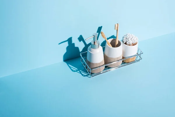 Zahnbürstenhalter mit Ohrstöpseln und Zahnbürsten mit Spender Flüssigseife im Badezimmerregal auf blauem Hintergrund, Zero-Waste-Konzept — Stockfoto