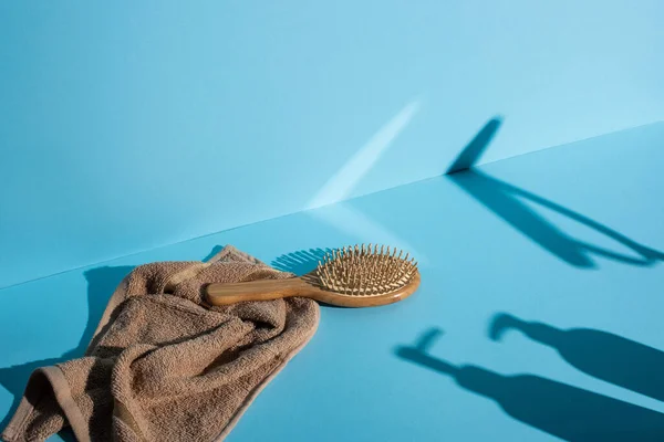 Щетка для волос на полотенце и тени на синем фоне, нулевая концепция отходов — стоковое фото