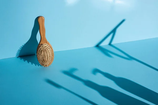 Hair brush and shadows on blue background, zero waste concept — Stock Photo
