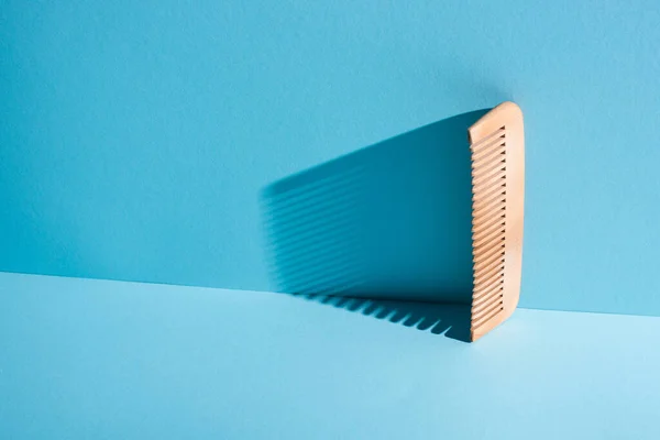 Peine de madera con sombra sobre fondo azul, concepto de cero residuos - foto de stock