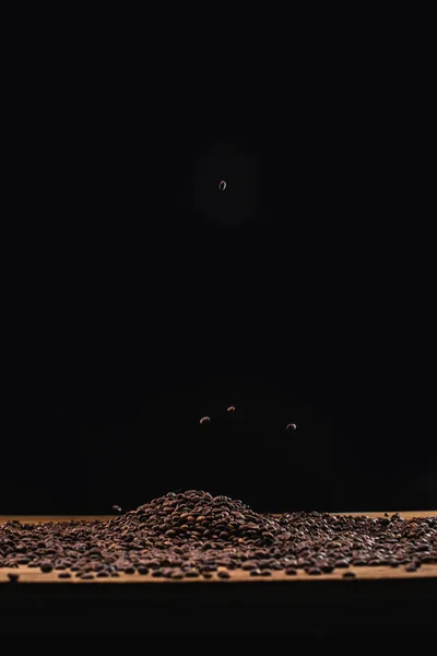 Жареные кофейные зерна в куче изолированы на черный — стоковое фото