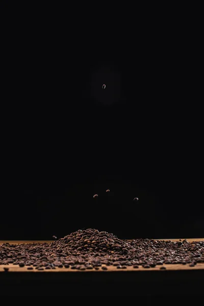 Roasted coffee beans in pile isolated on black — Stock Photo