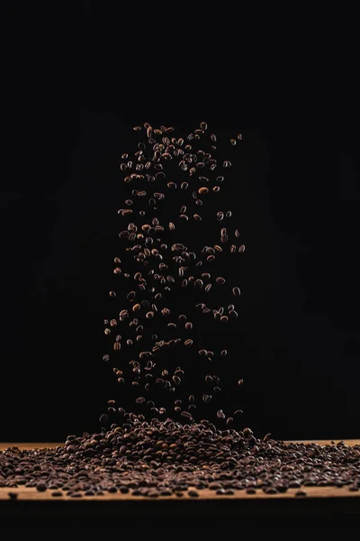 Granos de café tostados frescos en el aire aislados en negro - foto de stock