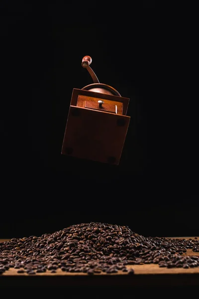 Macinacaffè sopra chicchi di caffè tostati freschi isolati su nero — Foto stock