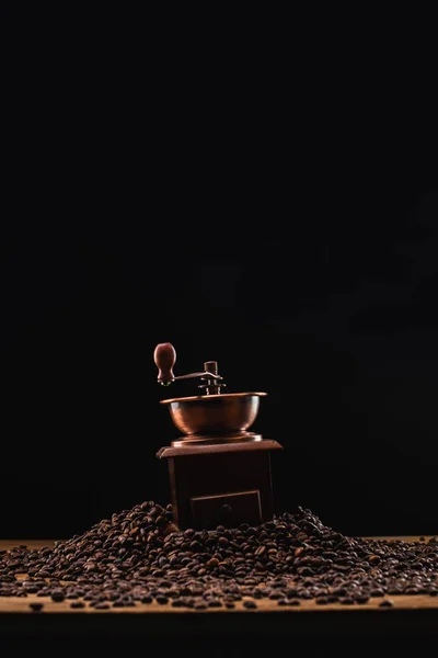 Moulin à café sur grains de café frais torréfié isolé sur noir — Photo de stock