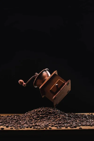 Moulin à café au-dessus des grains de café torréfiés frais isolés sur noir — Photo de stock