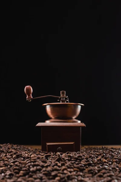 Foco seletivo do moedor de café em grãos de café torrados frescos isolados em preto — Fotografia de Stock