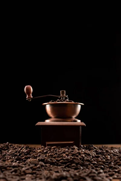 Foco seletivo do moedor de café em grãos de café torrados frescos isolados em preto — Fotografia de Stock