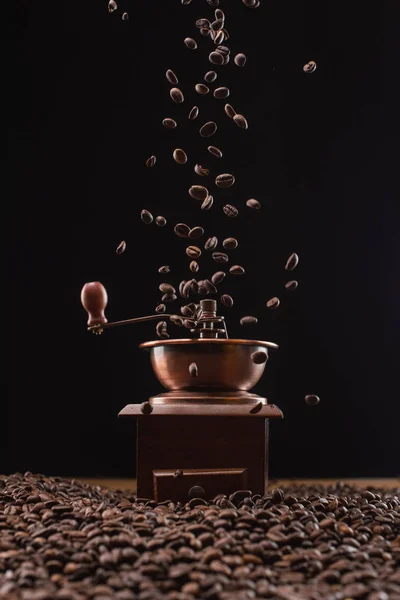 Moulin à café et grains de café frais torréfiés dans l'air isolé sur noir — Photo de stock