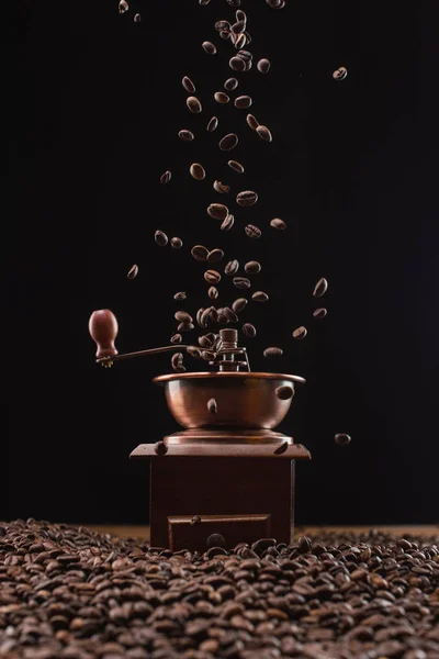 Moulin à café et grains de café frais torréfiés dans l'air isolé sur noir — Photo de stock