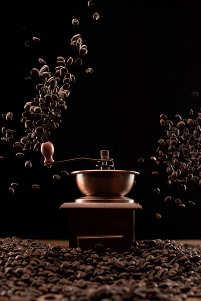 Coffee grinder and fresh roasted coffee beans in air isolated on black — Stock Photo