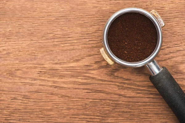 Vista dall'alto di chicchi di caffè torrefatto fresco e caffè macinato in portafiltro su tavolo di legno — Foto stock