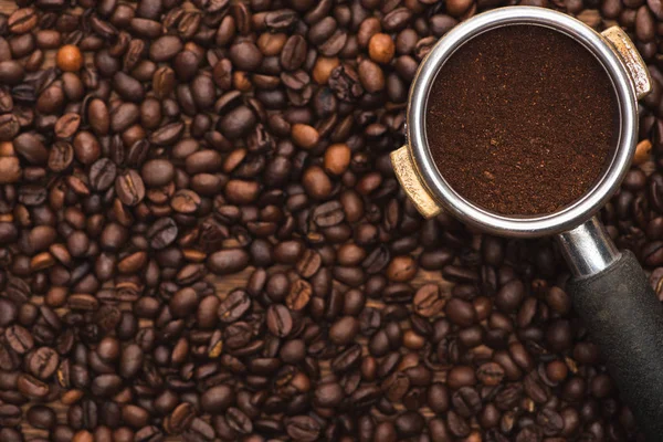 Top view of ground coffee in filter holder on fresh roasted coffee beans — Stock Photo