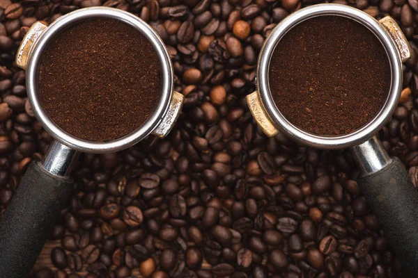 Vue du dessus des grains de café frais torréfiés et du café moulu dans le porte-filtre sur la table en bois — Photo de stock