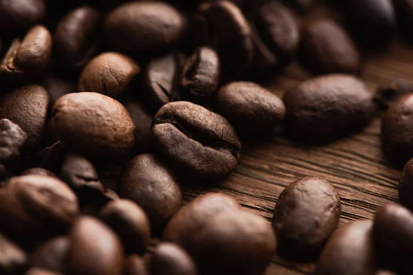 Крупним планом вид свіжих обсмажених кавових зерен, розкиданих на дерев'яному столі — стокове фото