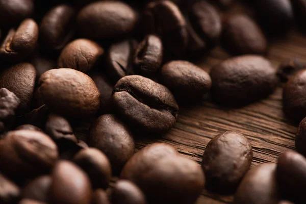 Close up view of fresh roasted coffee beans scattered on wooden table — Stock Photo