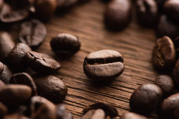 Close up view of fresh roasted coffee beans scattered on wooden table — Stock Photo