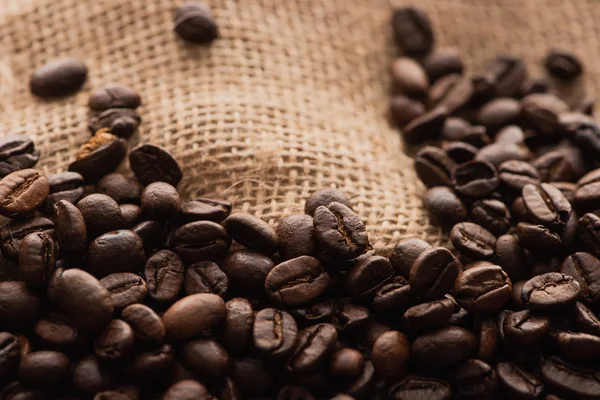 Vista de cerca de los granos de café tostados frescos en saco - foto de stock