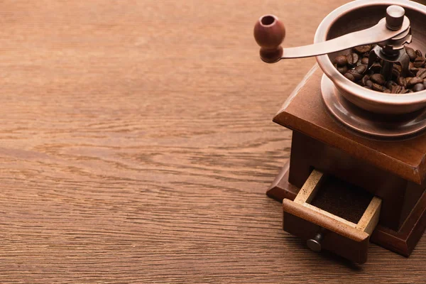 Grãos de café torrados frescos no moedor de café na mesa de madeira — Fotografia de Stock