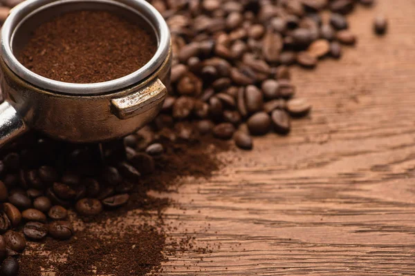 Close up view of fresh roasted coffee beans and ground coffee in filter holder on wooden table — Stock Photo