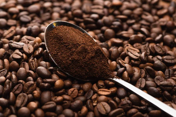 Messa a fuoco selettiva di chicchi di caffè tostato fresco e caffè macinato in cucchiaio — Foto stock