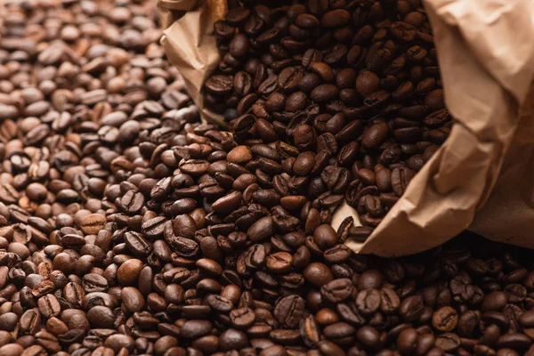 Grains de café frais torréfiés dispersés du sac en papier — Photo de stock