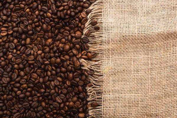 Vista superior de grãos de café torrados frescos e pano de saco — Fotografia de Stock