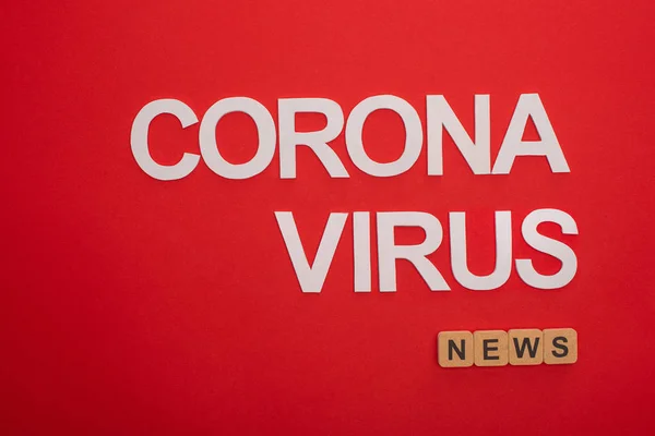 Draufsicht auf Coronavirus-Schriftzug mit Nachrichteninschrift auf Holzwürfeln auf rotem Hintergrund — Stockfoto
