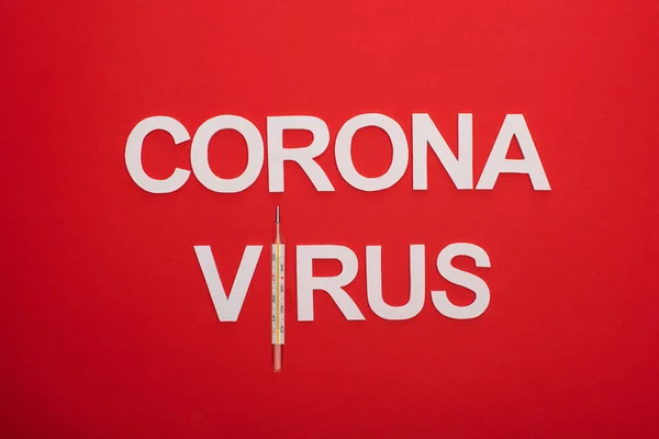 Vista dall'alto del coronavirus lettering con termometro isolato su rosso — Foto stock