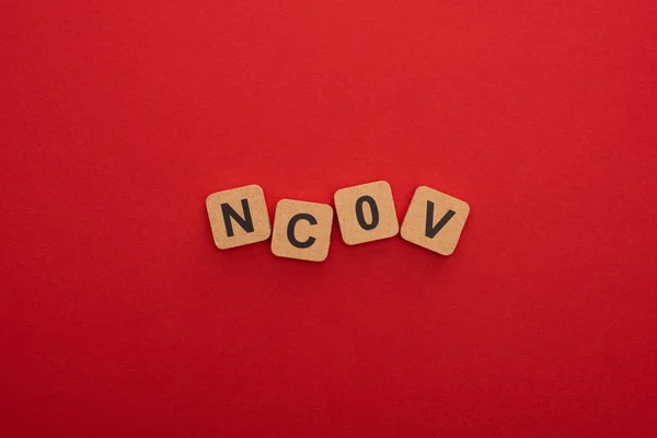 Vue du dessus des blocs de bois avec des lettres ncov sur fond rouge — Photo de stock