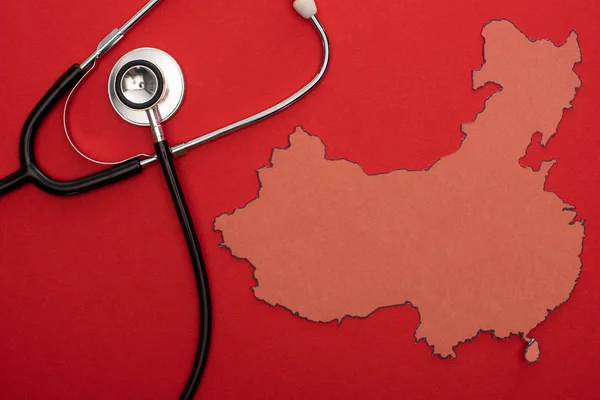 Vue du dessus de la mise en page de la carte de la Chine avec stéthoscope sur fond rouge — Photo de stock