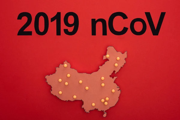 Top view of 2019 ncov lettering with layout of china map on red background — Stock Photo